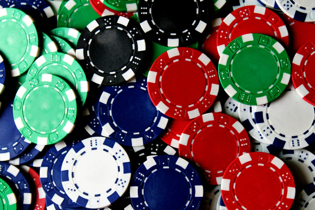 Ein Haufen bunter Pokerchips in verschiedenen Farben, die auf einen Tisch gestapelt sind.
